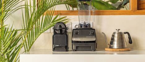 A kitchen counter with a blender, a coffee maker, and a potted plant.