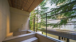 A modern bathroom with a freestanding bathtub, a wooden slatted ceiling, and a view of trees through large windows. - Brown Dot Hotel Gyeongju (Gyeongju)