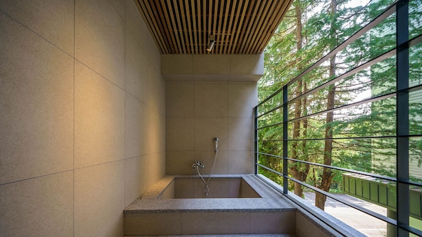 A modern bathroom with a built-in bathtub, a shower, and a window with a view of trees. - Brown Dot Hotel Gyeongju (Gyeongju)