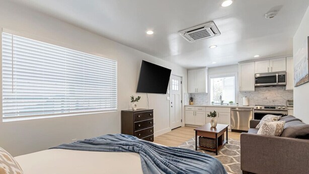 Un apartamento moderno con dormitorio, sala de estar y cocina.