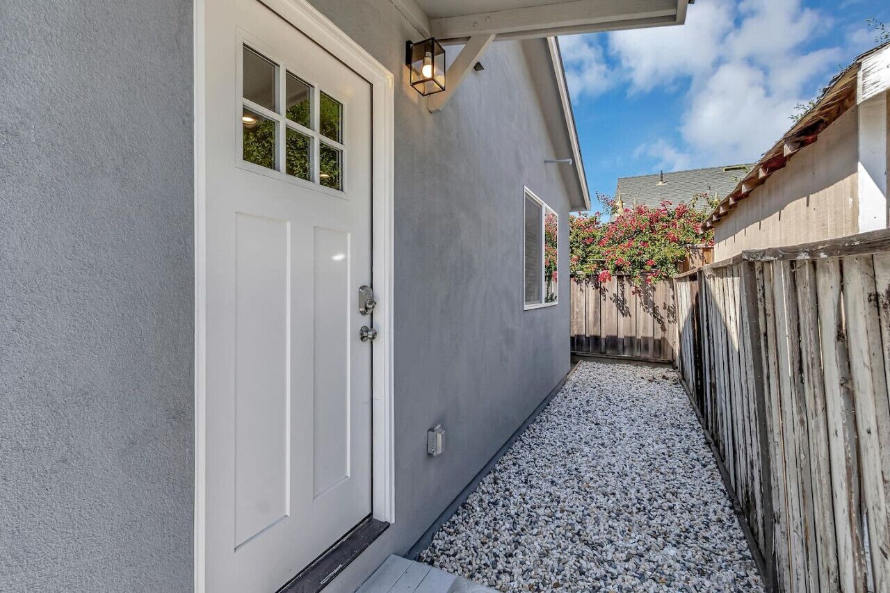 Une allée étroite mène à une maison avec une porte blanche et une petite fenêtre.