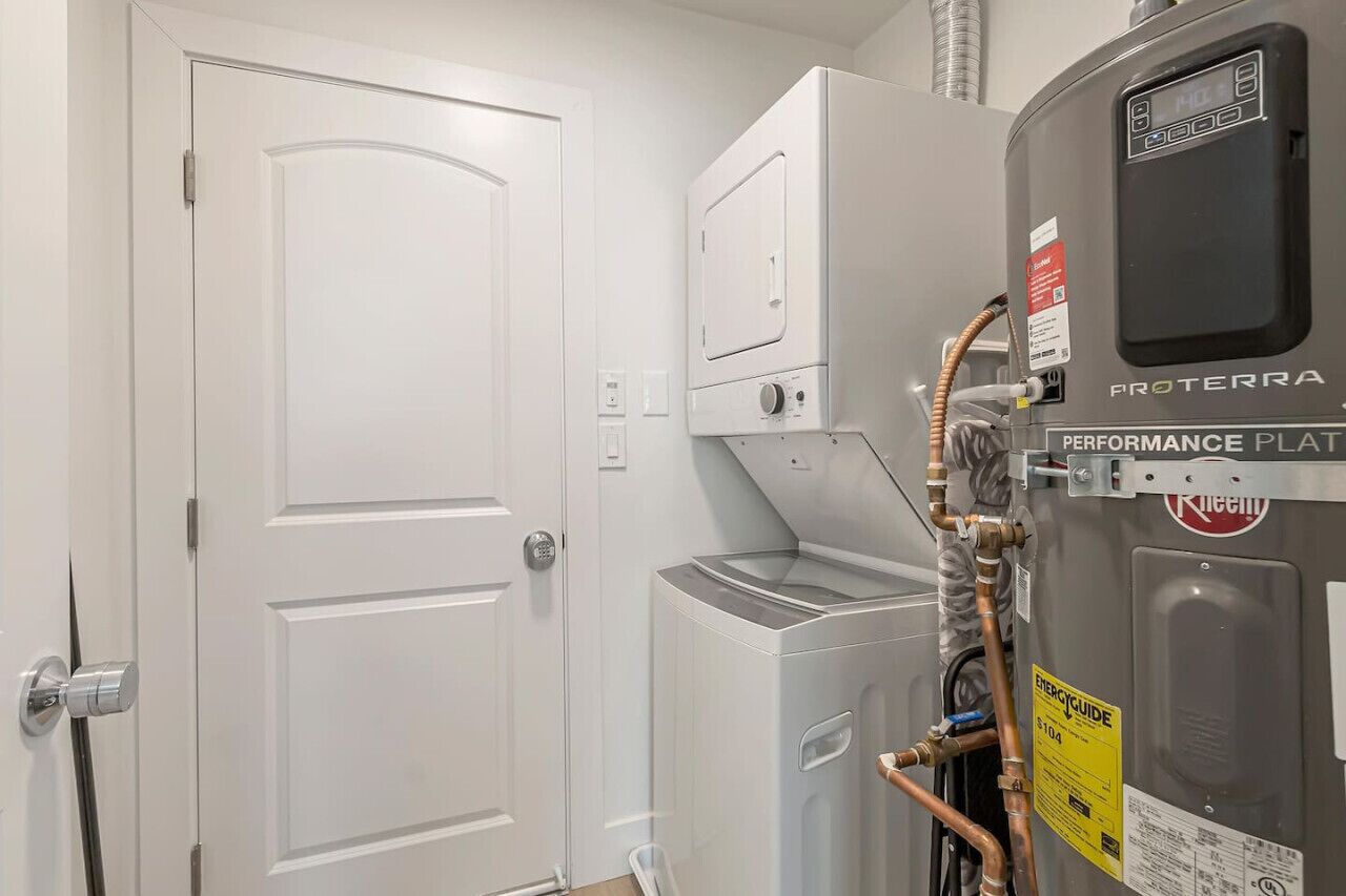 Una sala de lavandería con una lavadora Proterra Performance Plate, una secadora y una puerta blanca.