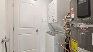 Una sala de lavandería con una lavadora Proterra Performance Plate, una secadora y una puerta blanca.
