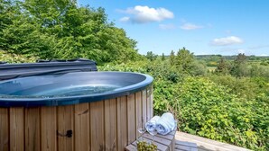 Ein Whirlpool auf einer Holzterrasse mit schöner Aussicht auf Grünflächen und Bäume.