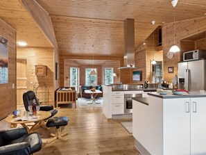 Un interior de cabaña moderno con detalles de madera, un comedor, una cocina y una sala de estar.