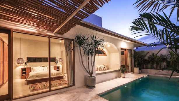 Una casa moderna con piscina, ventanas amplias y un dormitorio con cama y mesitas de noche.