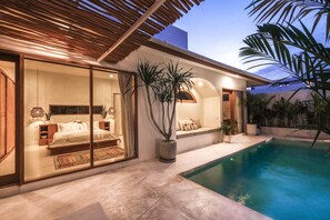 A modern house with a pool, large windows, and a bedroom with a bed and nightstands.