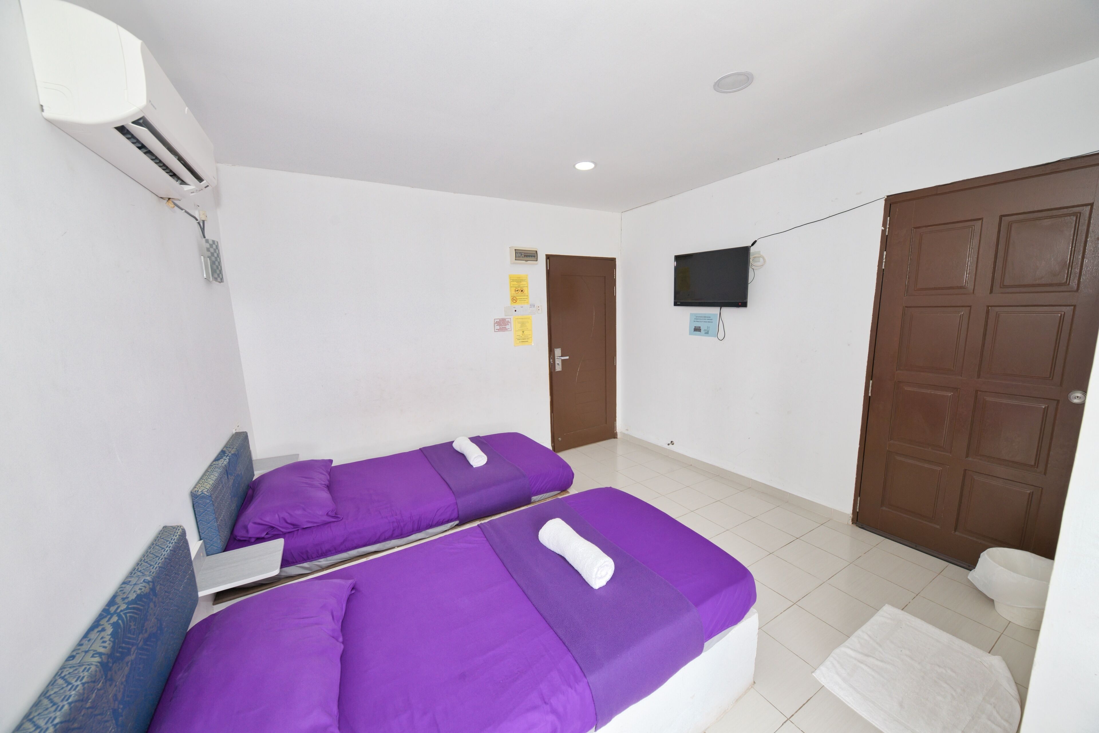 A room with two beds, a television on the wall, and a door.
