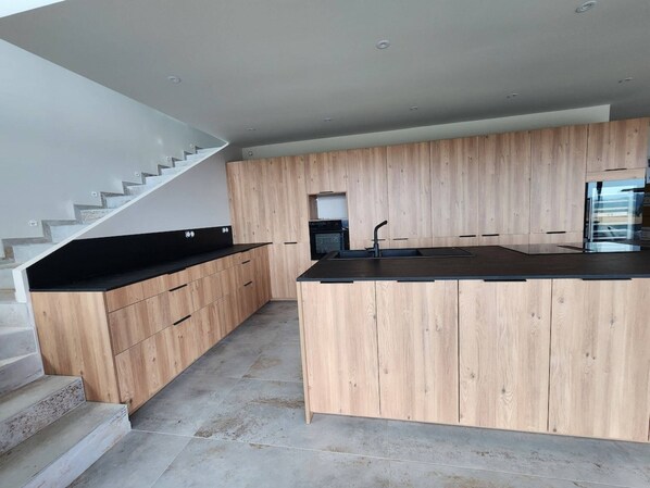 Una cocina moderna con armarios de madera, encimera negra y estufa empotrada.