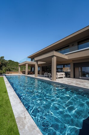 Uma casa moderna com piscina, área de estar ao ar livre e um pátio coberto.