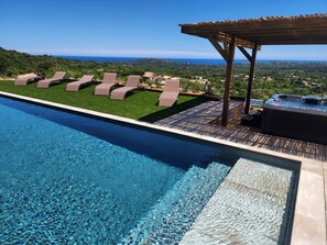 Piscina com água cristalina, rodeada por espreguiçadeiras e uma pérgola de madeira.