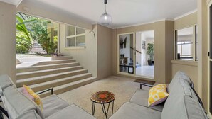 A spacious living area with a sofa, a small table, and a staircase leading to an upper level. - Spacious 4-Bed Family Retreat with Pool Near Beach (Coolum Beach)
