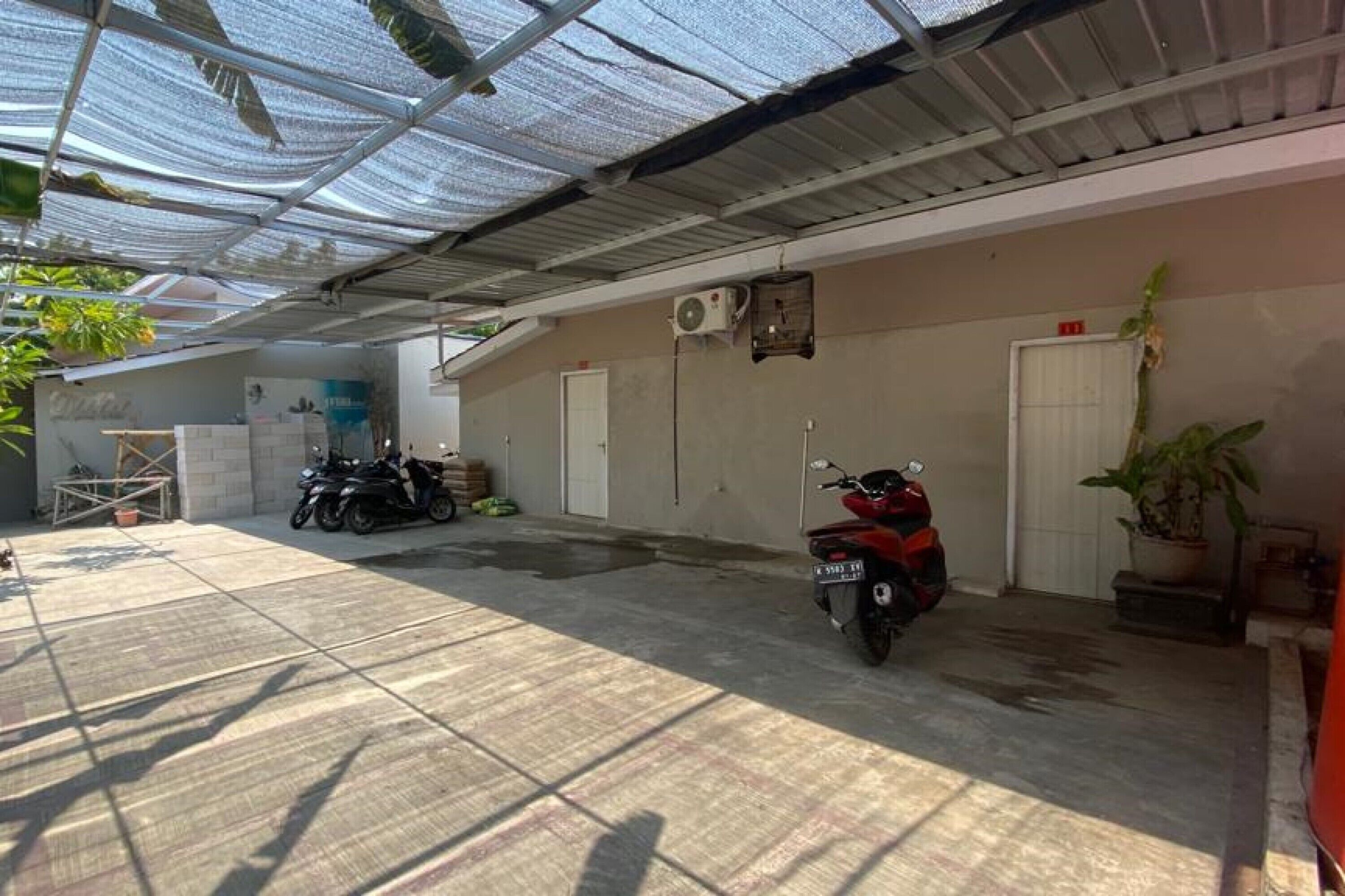 A covered parking area with a motorcycle and a scooter parked.