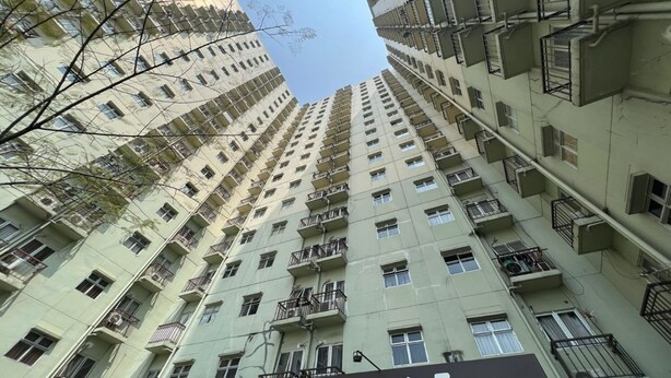 Een hoog gebouw met meerdere balkons en een bord waarop staat: WELCOME LOBBY E.