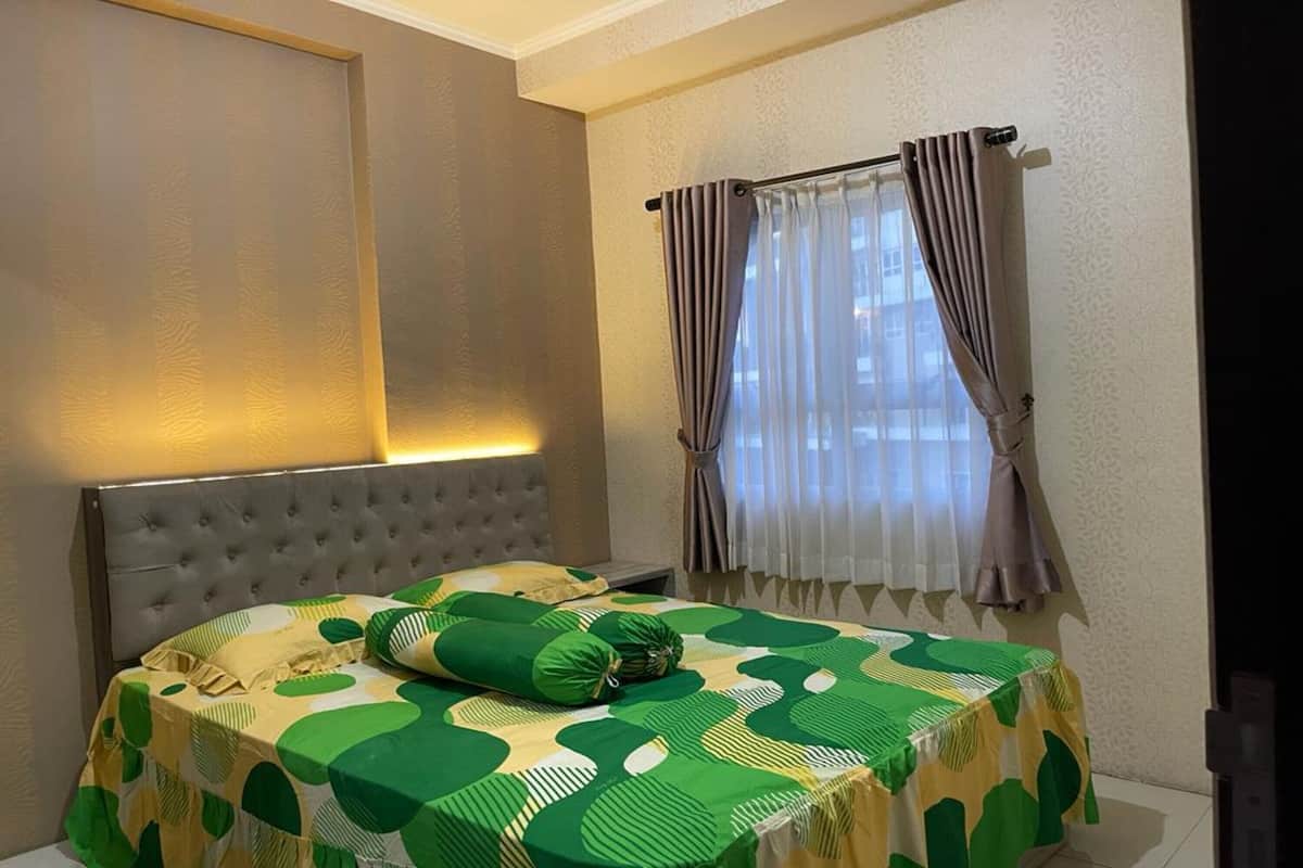 Una habitación de hotel con cama, ventana con cortinas y pared con textura.
