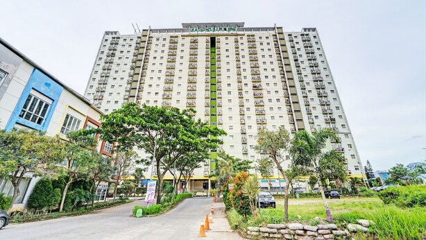 Un hôtel de grande hauteur doté de nombreux balcons, d’une entrée principale et entouré de verdure.