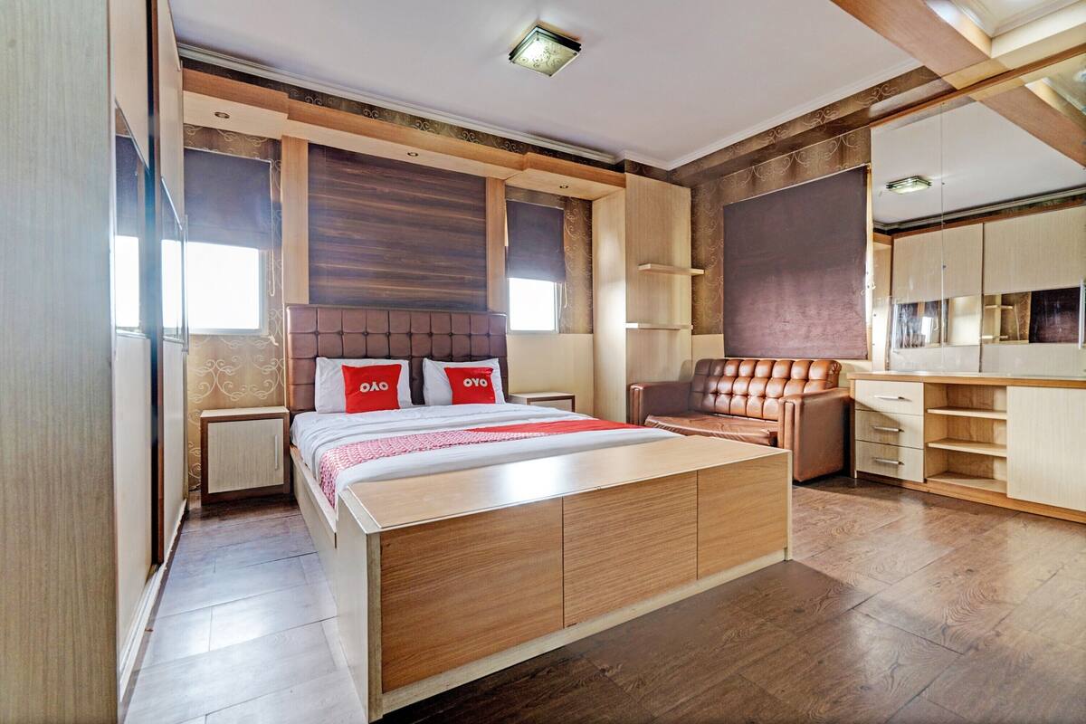 Ein modernes Schlafzimmer mit einem großen Bett, einem Holzkopfstück, einer Sitzecke und einem integrierten Kleiderschrank.