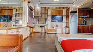 Une cuisine moderne avec des meubles en bois, un téléviseur encastré et un réfrigérateur.