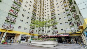 Un hôtel de grande hauteur doté de nombreux balcons, d’un hall d’entrée et d’un petit jardin.