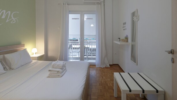 Habitación de hotel con cama, mesita de noche, ventana con cortinas, vista al balcón exterior y un equipo de aire acondicionado.