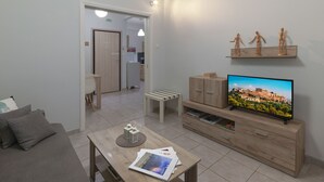 Una sala de estar moderna con televisor de pantalla plana, muebles de madera y vista a un paisaje urbano.
