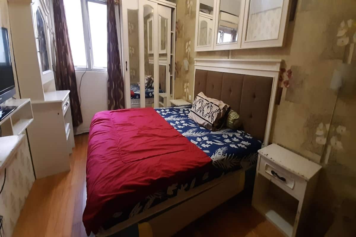 Une chambre à coucher comprenant un lit, une table de chevet, une armoire et un téléviseur.