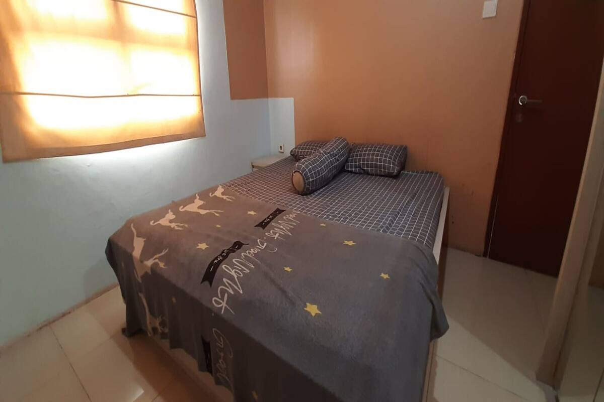 Une chambre à coucher avec un lit, une table de chevet, une fenêtre avec des stores et une porte.