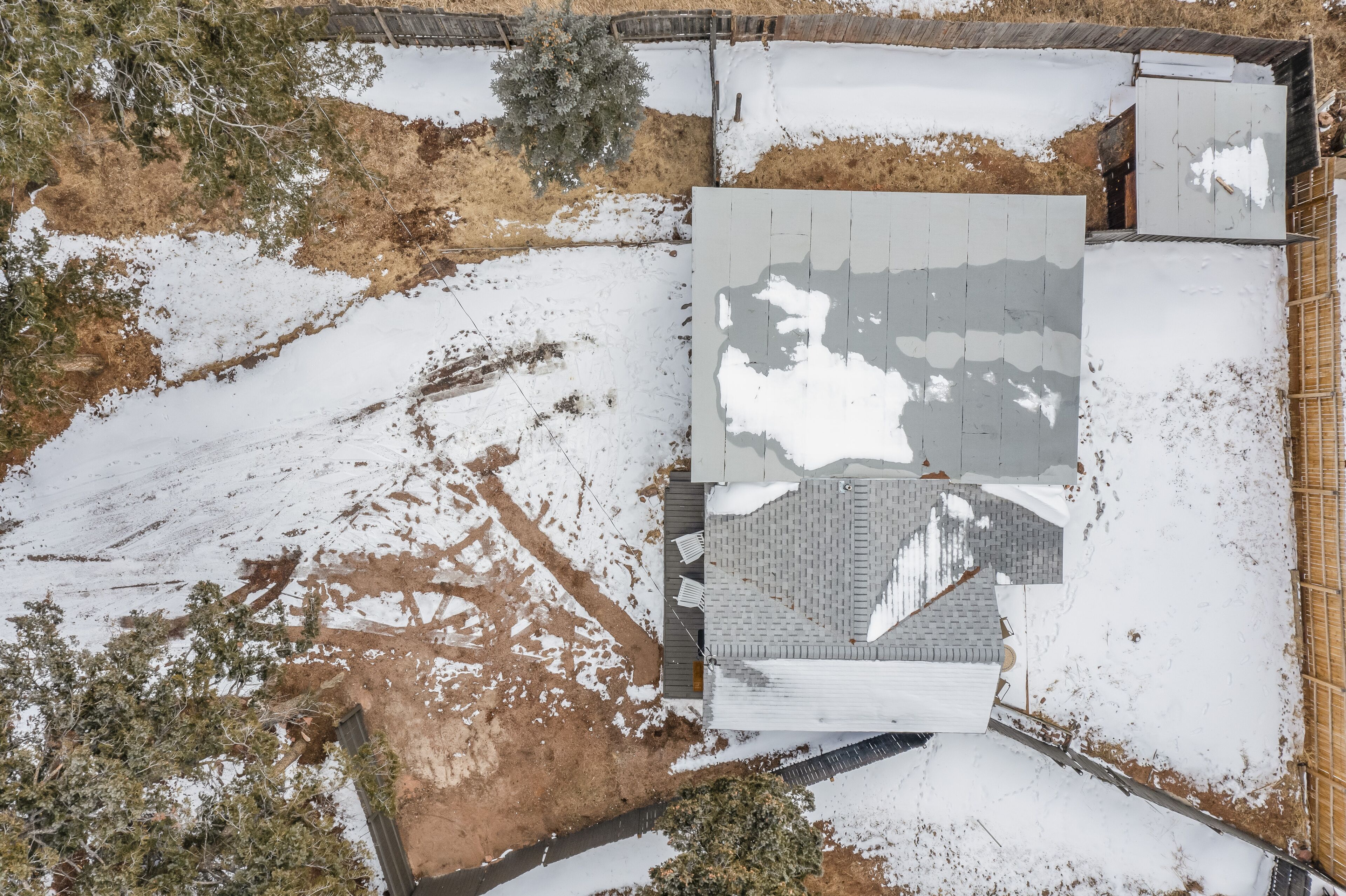 Vue aérienne d’un quartier résidentiel, avec une maison dotée d’un toit en pente et d’une cour clôturée.