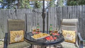 Un patio con dos sillas, una mesa y una valla de madera al fondo.