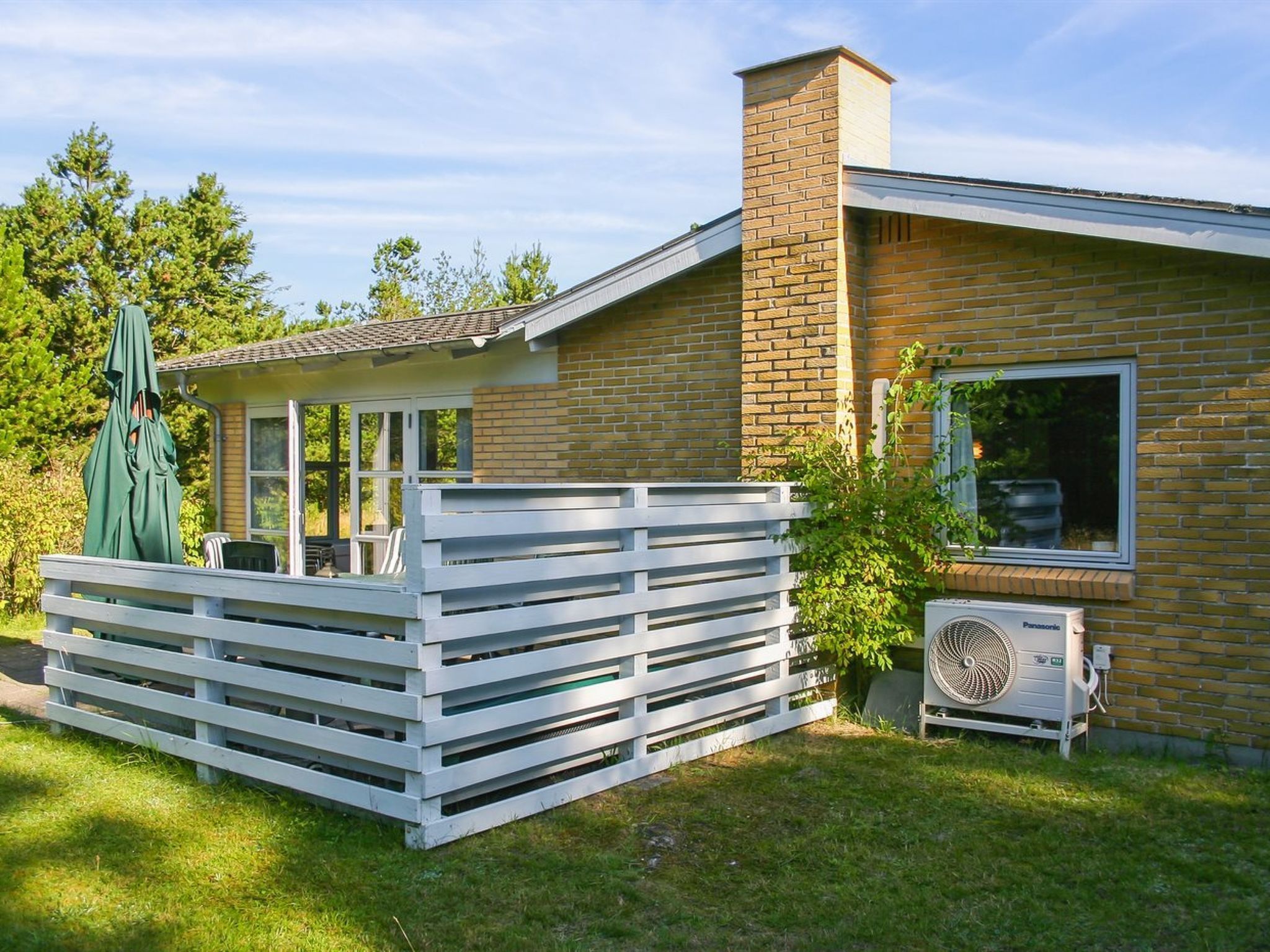 A house with a brick exterior, a covered patio with outdoor furniture, and a large window.