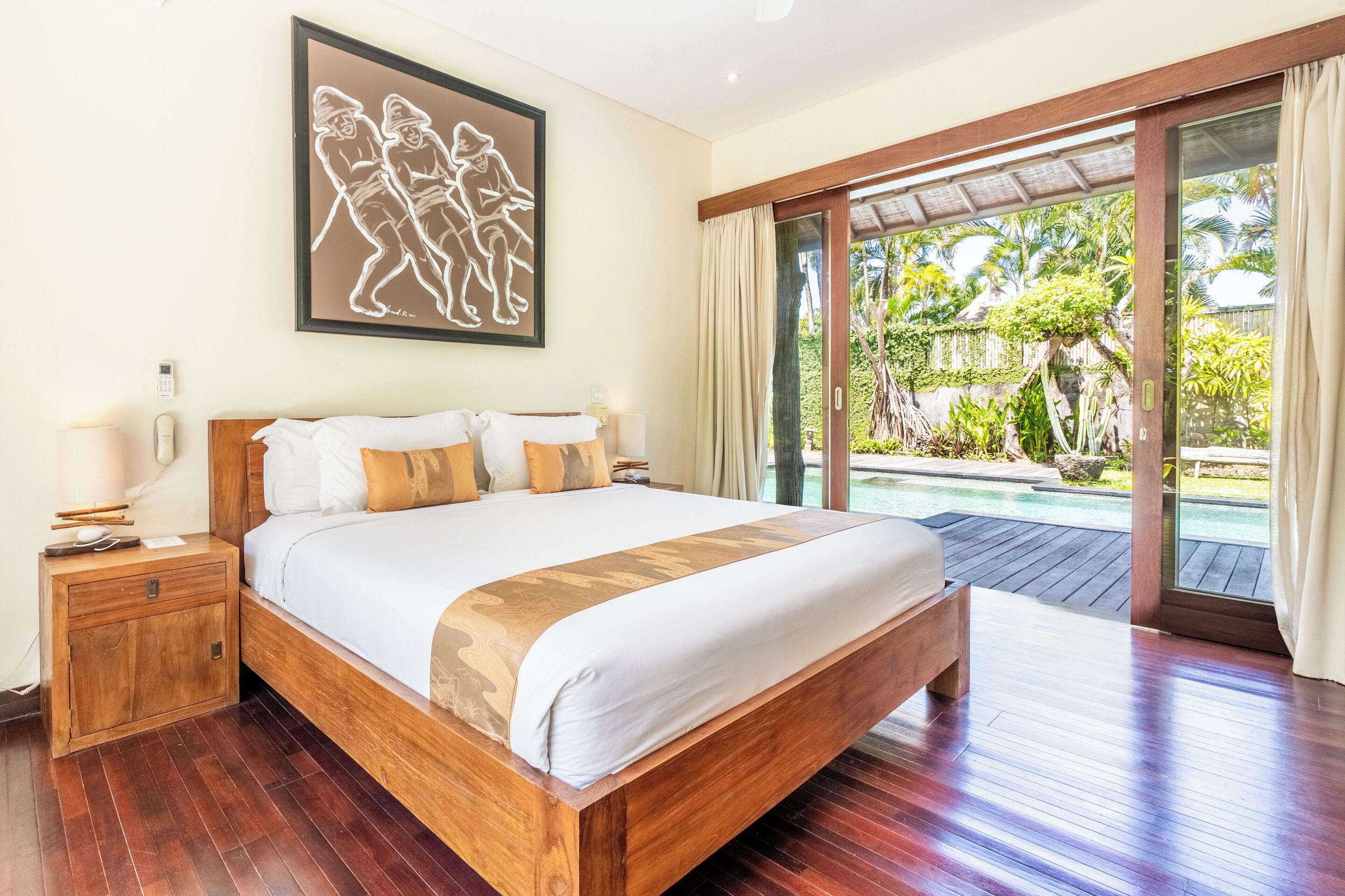 Ampia camera da letto con un letto grande, comodini in legno e vista su piscina e giardino tropicale.