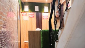 Un escalier étroit, recouvert d’une moquette verte, mène à un espace d’accueil.
