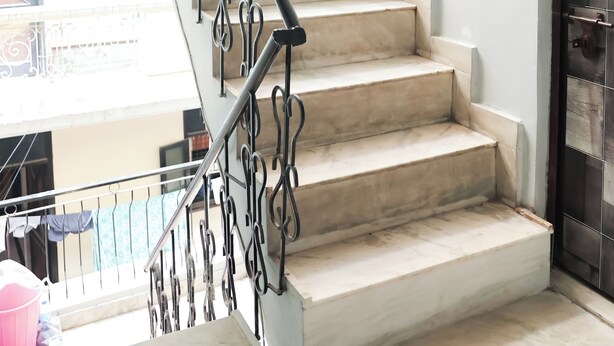 Un escalier avec une rampe en métal et des marches de couleur beige.