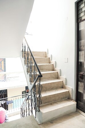 A staircase with a metal railing and beige steps leading to a dark door.