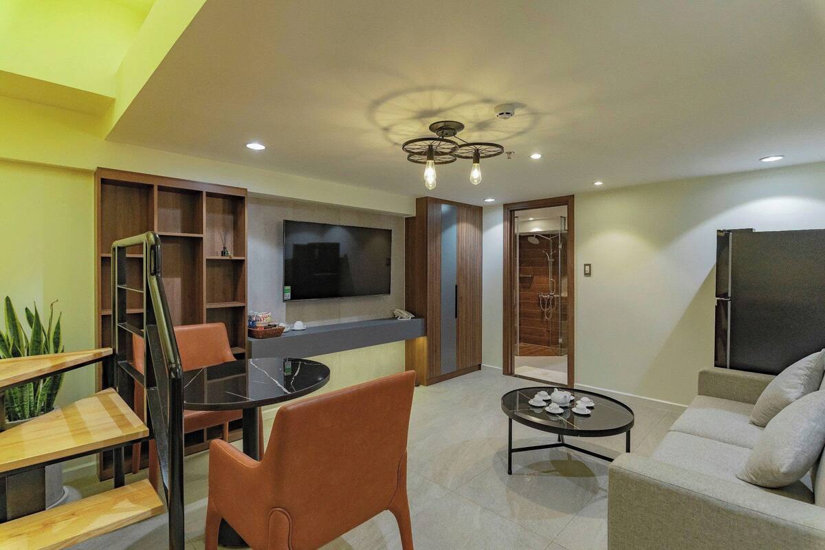 A modern living room with a flat-screen TV, a dining area with a table and chairs, and a sofa.
