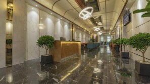 A hotel lobby with marble flooring, a reception desk, and potted plants. - The Elite Hotel (Xuan Huong - Da Lat)