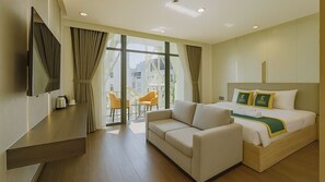 A hotel room with a bed, a sofa, a TV, a balcony with chairs, and a city view. - The Elite Hotel (Xuan Huong - Da Lat)