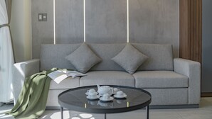 A modern living room with a grey sofa, a round coffee table, and a book. - The Elite Hotel (Xuan Huong - Da Lat)