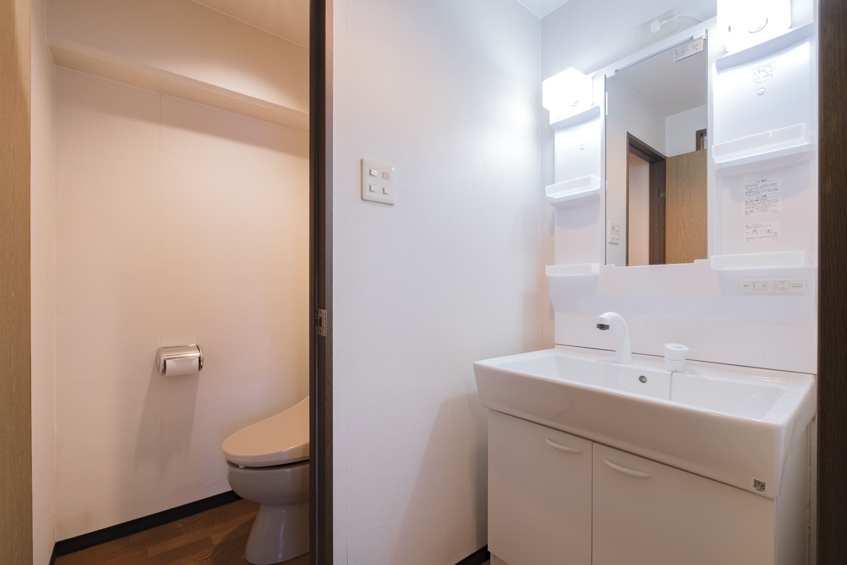 A bathroom with a toilet, sink, and mirror.