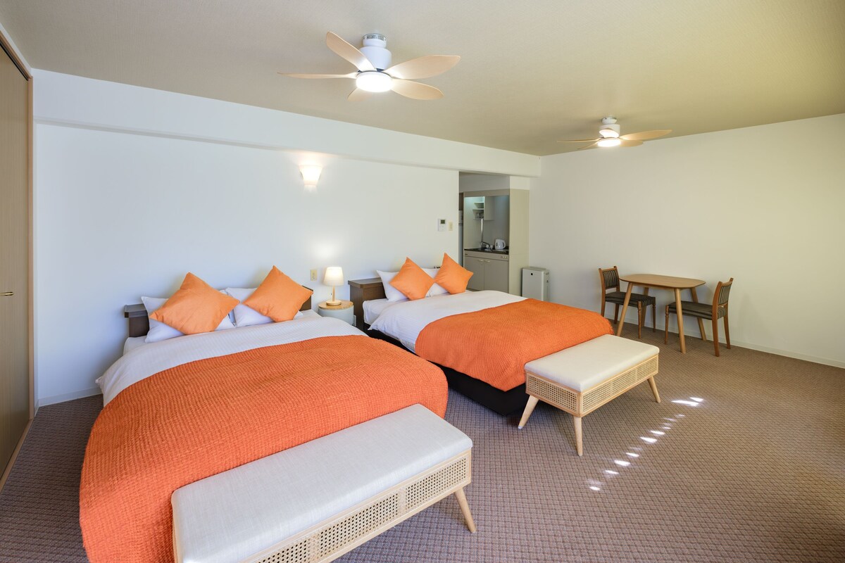 Une chambre d’hôtel avec deux lits, une table à manger et un ventilateur de plafond.