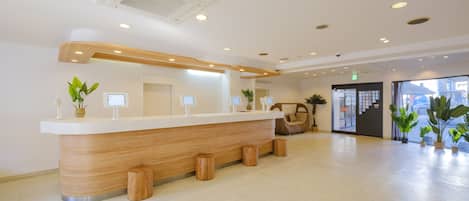 A reception desk with a wooden finish, a white counter, and a modern ceiling design with recessed lighting.