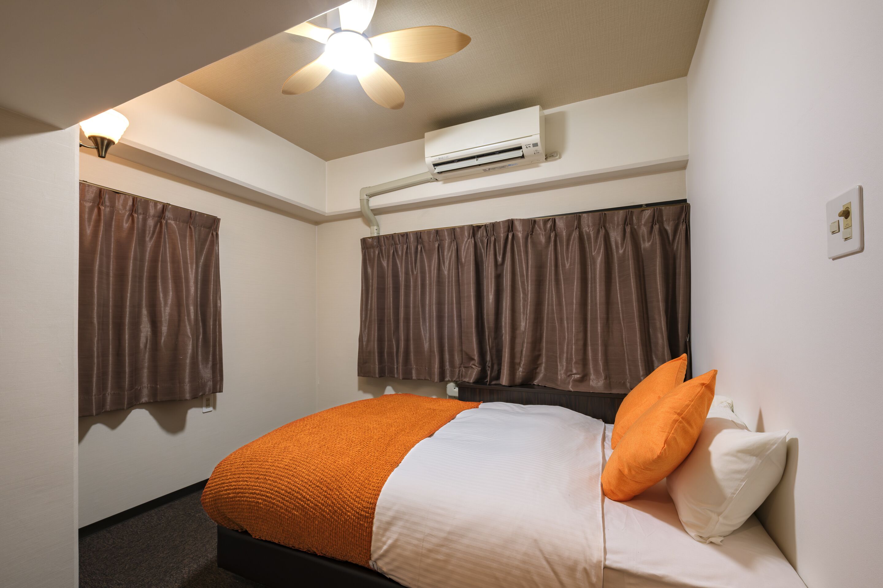 Una habitación de hotel con cama, aire acondicionado y ventilador de techo.