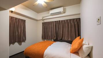 Una habitación de hotel con cama, aire acondicionado y ventilador de techo.