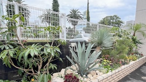 Een aangelegde tuin met verschillende planten en bloemen, een bakstenen muur en een metalen hek.