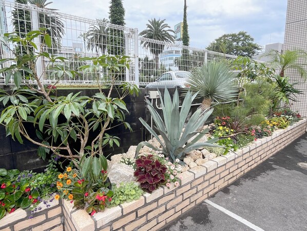 Un jardin aménagé avec différentes plantes et fleurs, un mur en briques et une clôture en métal.