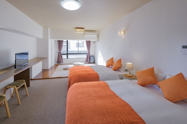 Een hotelkamer met twee bedden, een bureau, een stoel en een kleine tafel met een lamp.