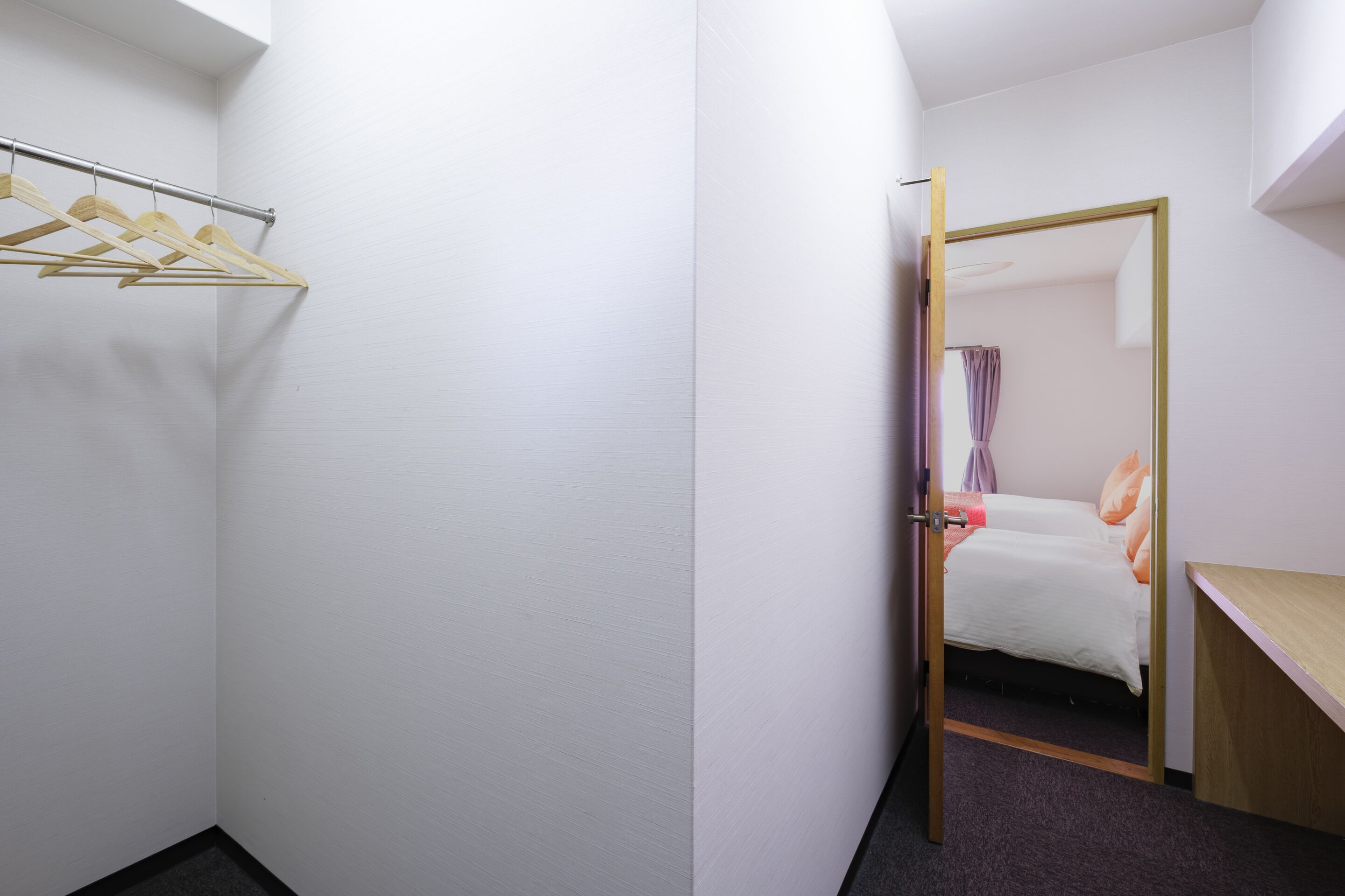A hotel room with a closet, a bed, and a desk.