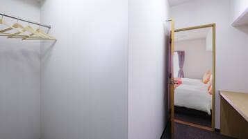 A hotel room with a closet, a bed, and a desk.