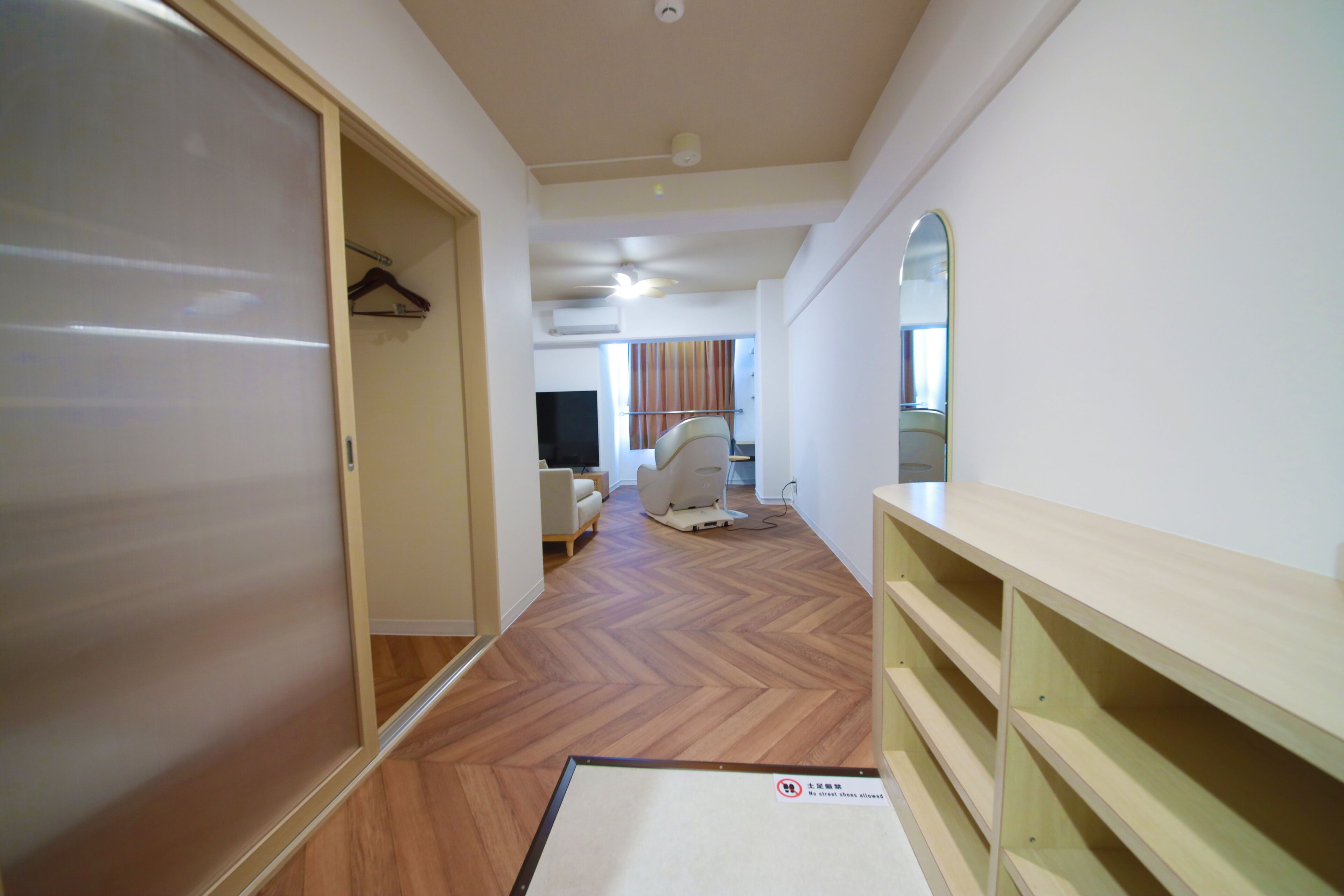A hallway with a wooden floor, a sliding door, and a mirror on the wall.