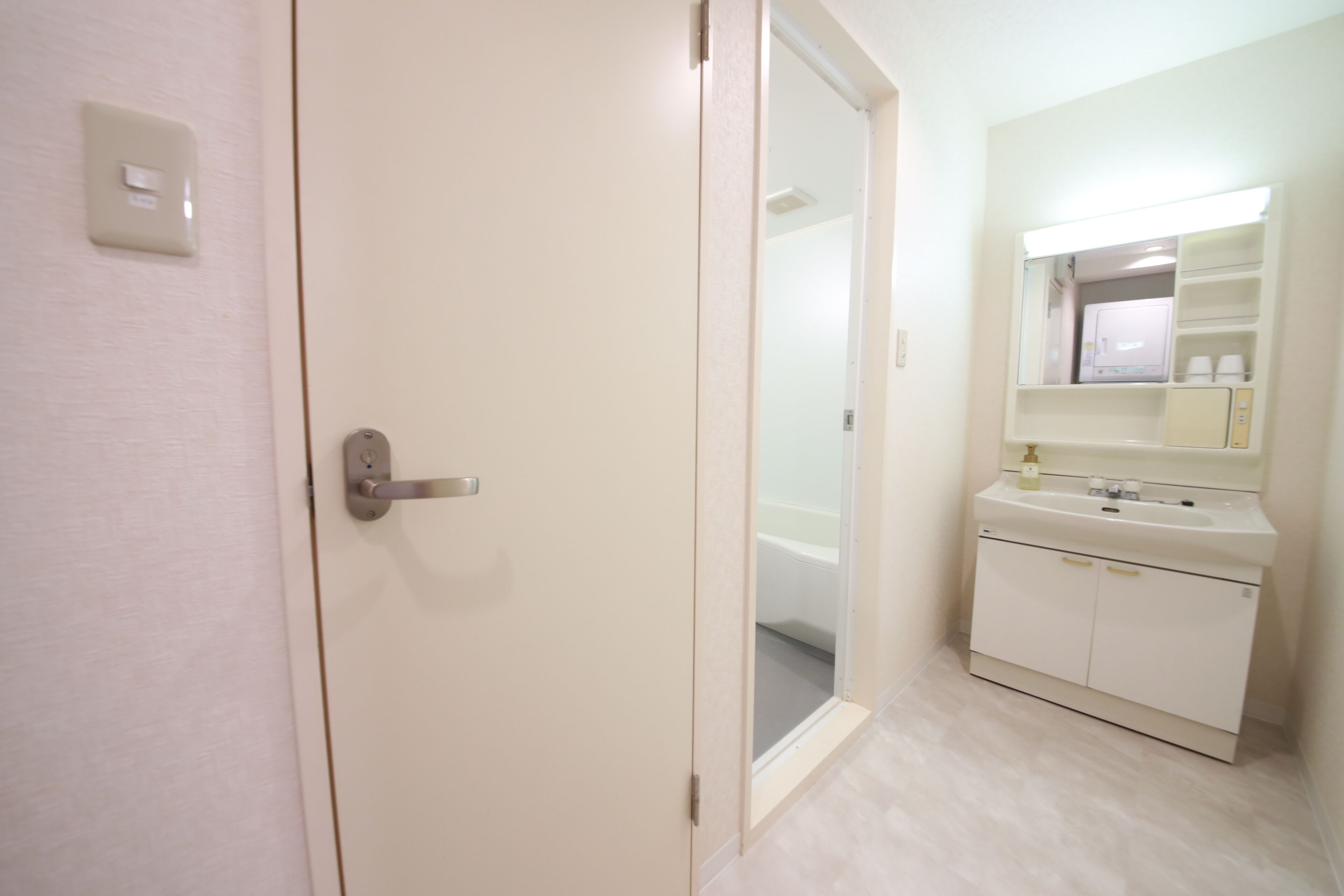 A bathroom with a white sink, mirror, and a door leading to another room.